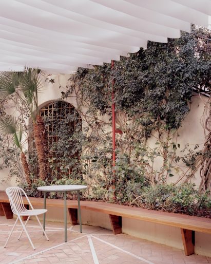 Courtyard of Myrto pizzeria with white chair and green table
