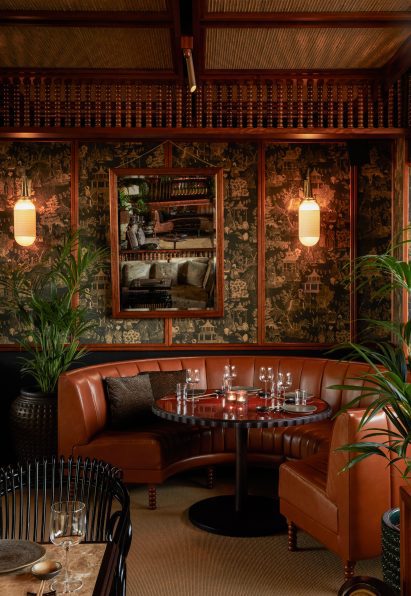 Restaurant seating area with curved leather booth, printed wallpaper and wooden joinery by Pirajean Lees