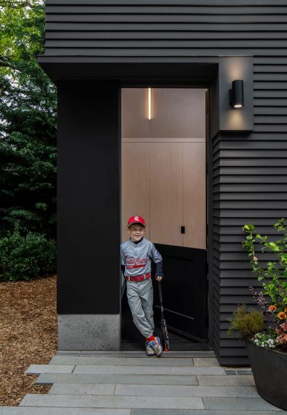 A boy stands in the doorway of a black shed