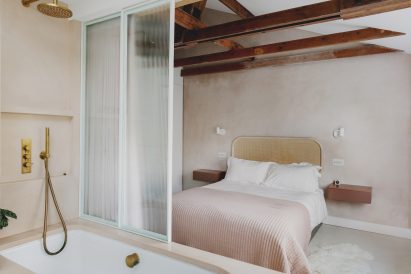 Studio Hagen Hall 1970s-style townhouse bedroom with a bathtub and glass screen