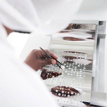 A photograph of a person placing pearls into a decorative piece