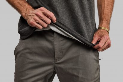 Man holding up hem of dark grey T-shirt with white interior