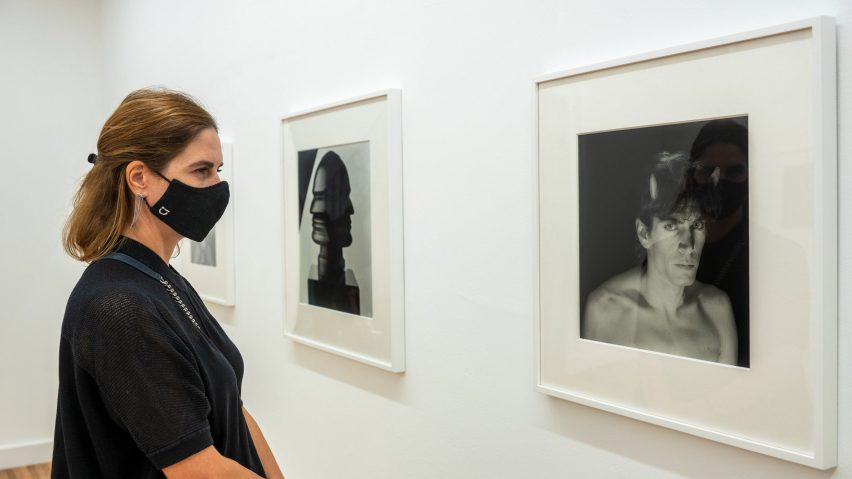 A woman viewing photographs in frames in a white gallery