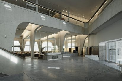 A welcome desk in the double height lobby sits in front of large glass walls