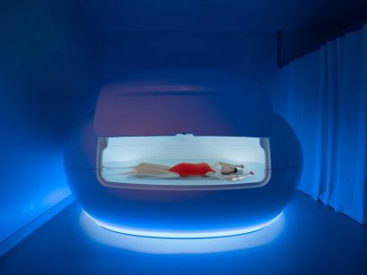 Sensory deprivation pod tinged in blue light in spa interior by Bureau