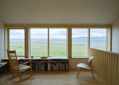 A wood-lined living room overlooking a nature reserve