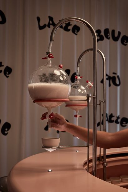 Hand pulling milk from circular beakers in installation by Lolita Gomez and Blanca Algarra Sanchez