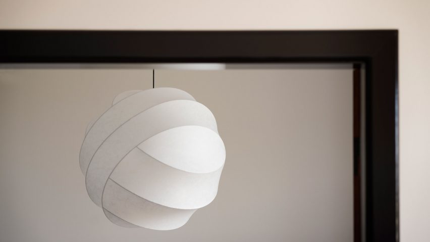 A white pendant light in front of a mirror