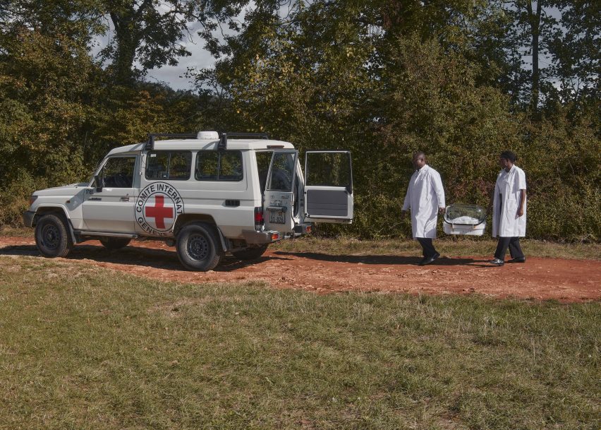 Two medics carry an incubator to an ambulance