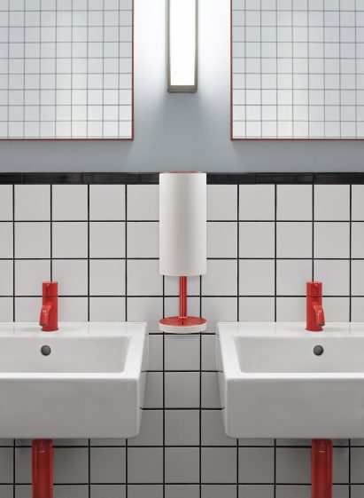 Red and white wall-mounted RS11 dispenser between basins in a public restroom