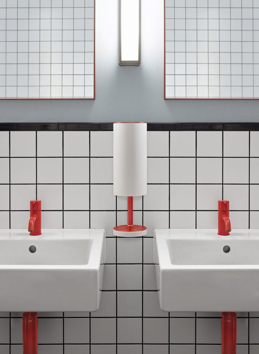 Red and white wall-mounted RS11 dispenser between basins in a public restroom