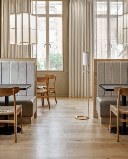 White freestanding hand sanitiser station in a light-filled contemporary restaurant