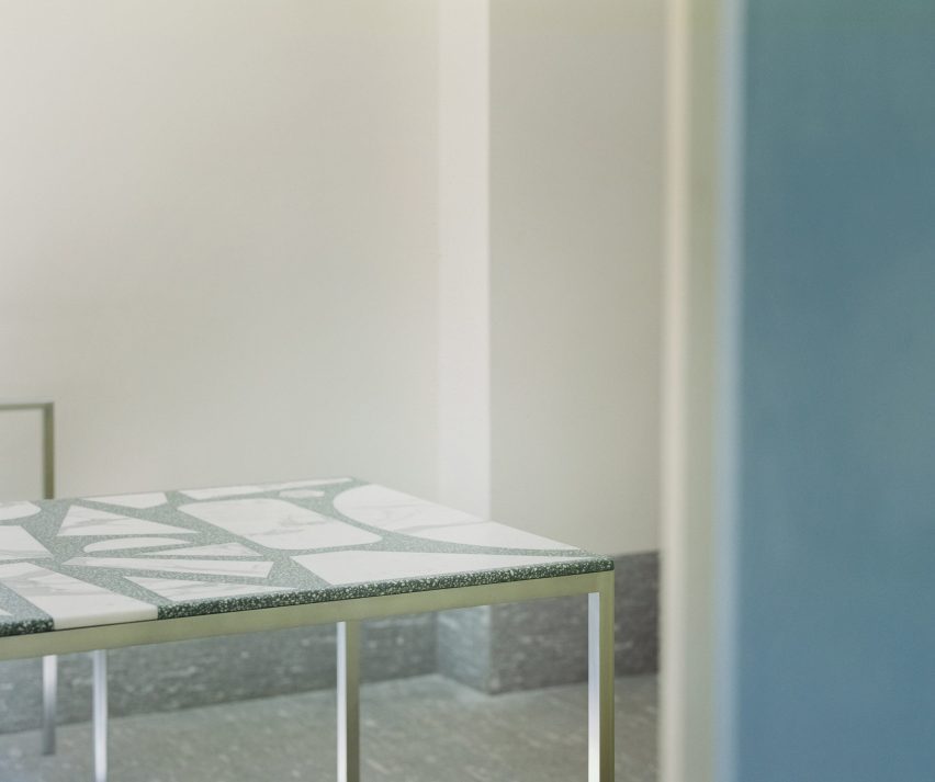 Dining table with green top embedded with large pieces of waste stone