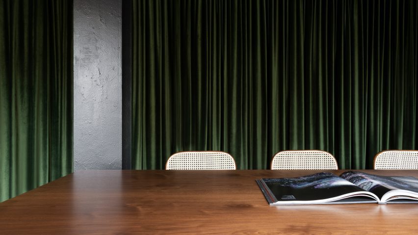Detail image of dark wooden table and green curtain in office by Tala Fustok Studio