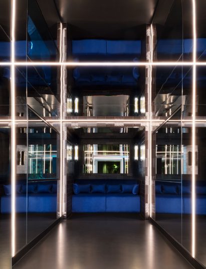 A dark corridor with mirrored walls and blue furnishings