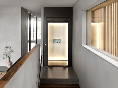 A photograph of illuminated Homelift elevator at top of stairs in a home