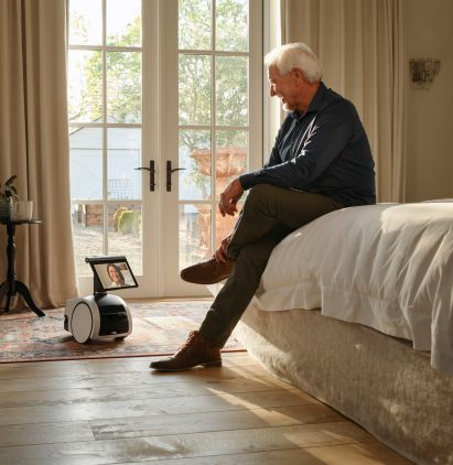 An elderly man talks to the Astro robot