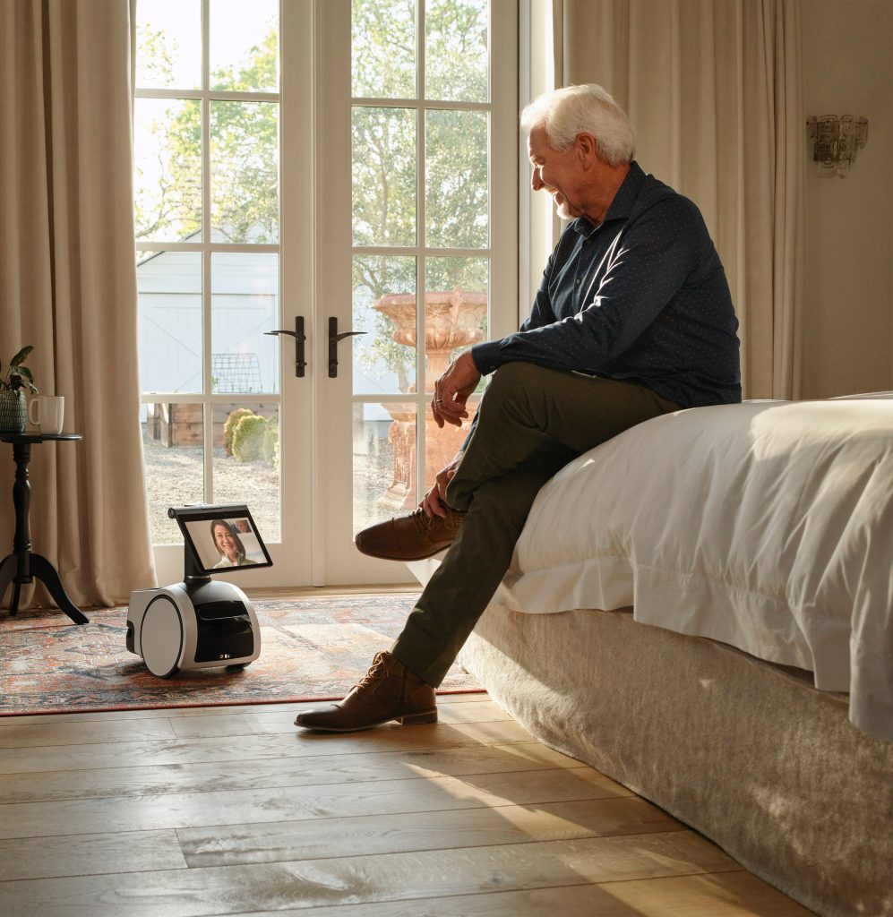 An elderly man talks to the Astro robot