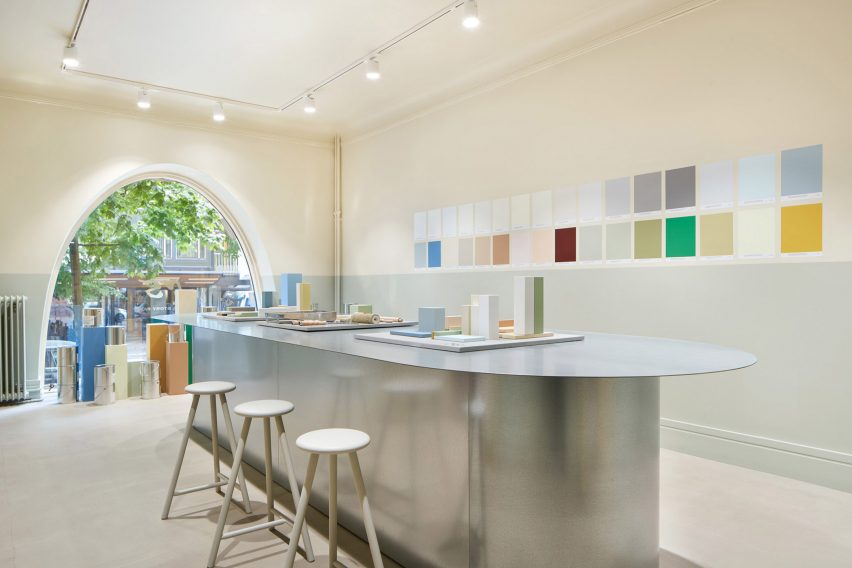Galvanised steel table in a sparse interior, with an arched window overlooking the street