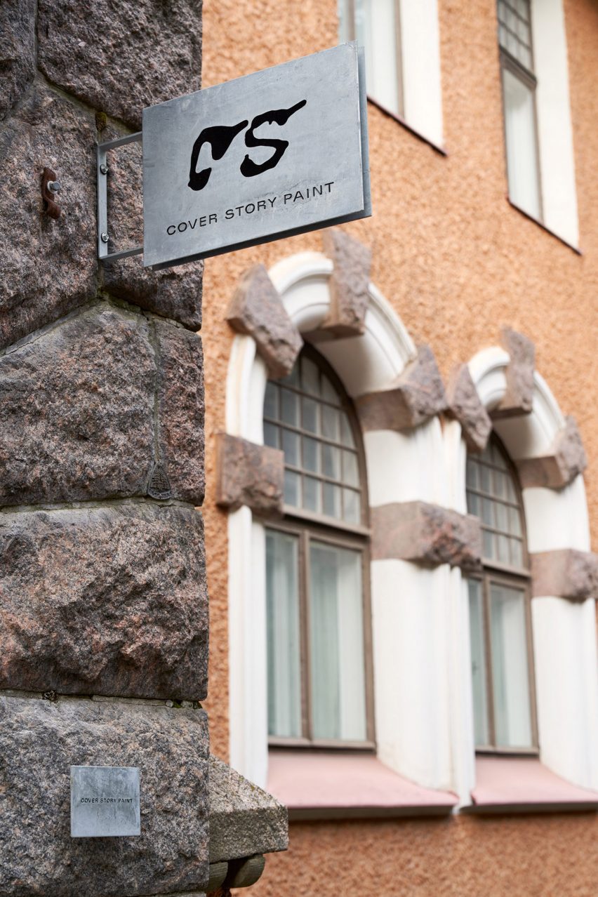 Cover Story metal sign hanging from the stone wall outside of a Helsinki building