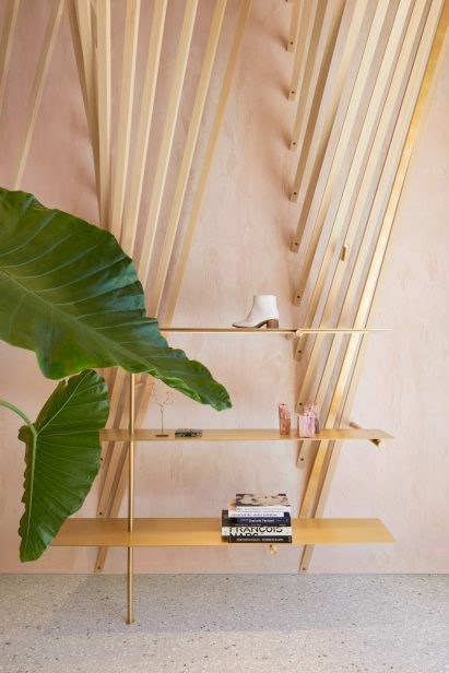 Brass display shelf in front of wall-mounted wooden fins in Forte dei Marmi retail space