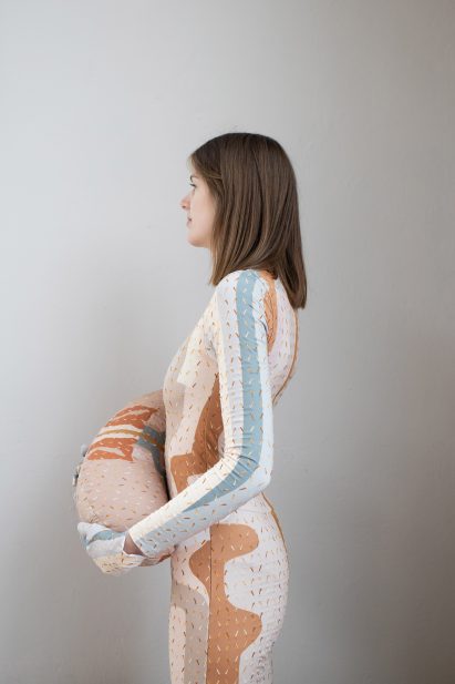 Woman wearing a Healing Imprint therapeutic garment with a meridian print and holding a matching pillow