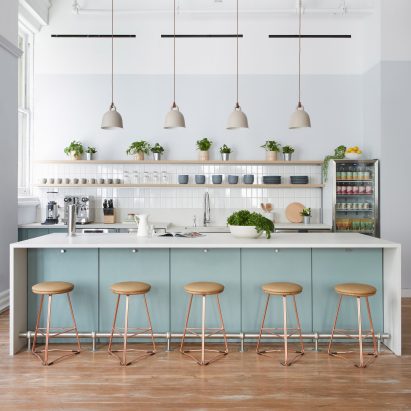 Interior of the cafe area of a medical office, which has white-washed walls and a pale blue counter with stools