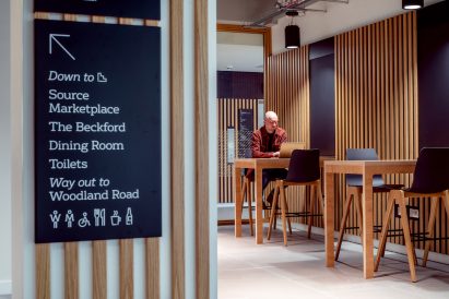 A photograph of Senate House by Feilden Clegg Bradley Studios wayfinding sign in corridor