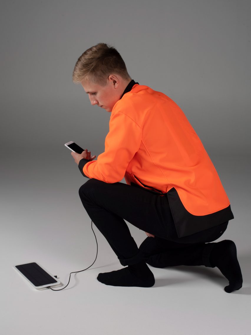 Man in orange jacket charges electronic devices