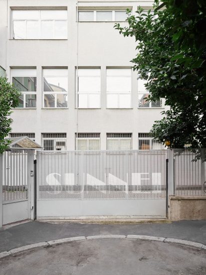 A gate to the headquarters is branded with the Sunnei logo