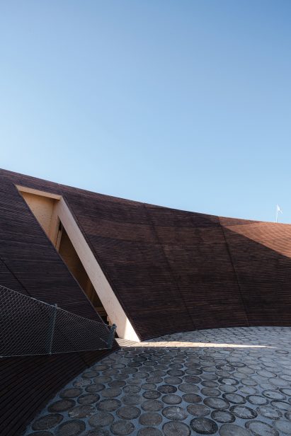 Interior courtyard of the Helsinki Biennial Pavilion paved with silver-coloured crosscut logs