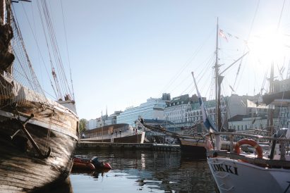 Helsinki's South Harbour with an old wooden ship in the foreground and the circular timber Helsinki Biennial Pavilion in the background