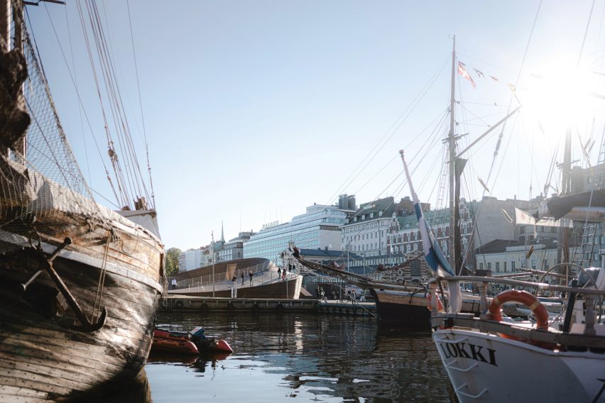 Helsinki's South Harbour with an old wooden ship in the foreground and the circular timber Helsinki Biennial Pavilion in the background