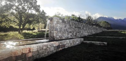 Water runs from a stone wall at the alpine garden