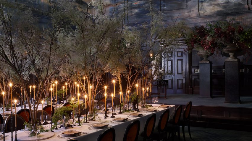 A photograph of a dining table filled with shrubbery and candles
