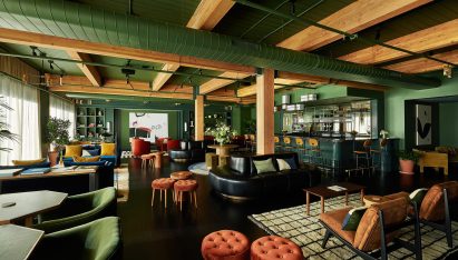 Lounge of Chief Chicago clubhouse with exposed timber beams, green walls and multicoloured seating