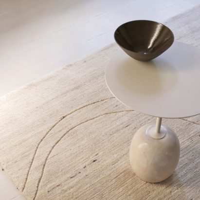 A cream coloured rug underneath a table