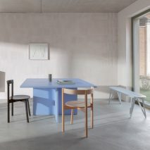 A photograph of Jazz dining chairs around a blue table in a naturally lit room