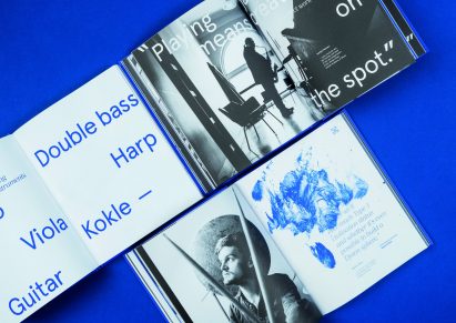 Pages of the publication 100 Years of the Jazeps Vitols Latvian Academy of Music showing a blue paint smear graphic and black and white full-page photography