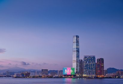 M+ museum LCD screen lit up with the M+ logo on the Victoria Harbour waterfront at dusk