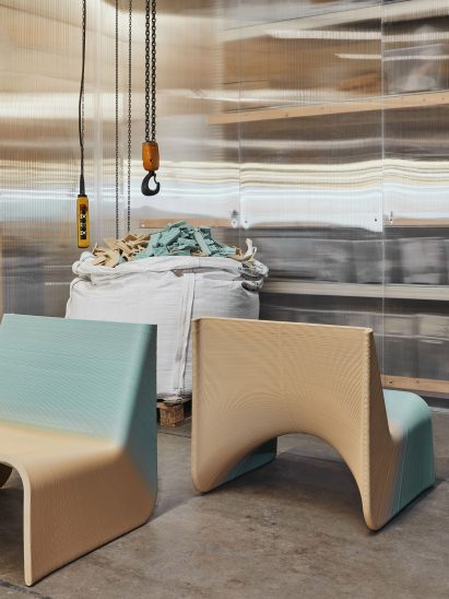 Two yellow and blue Ermis chairs in front of a bag of 3D-printing offcuts