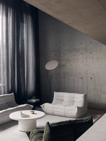 White and green Togo seating in front of concrete wall in residential conversion by Studio Goss