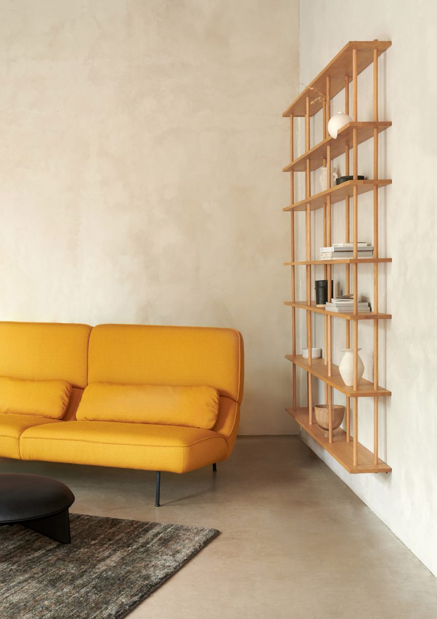 Velar sofa in yellow next to a wooden wall shelf