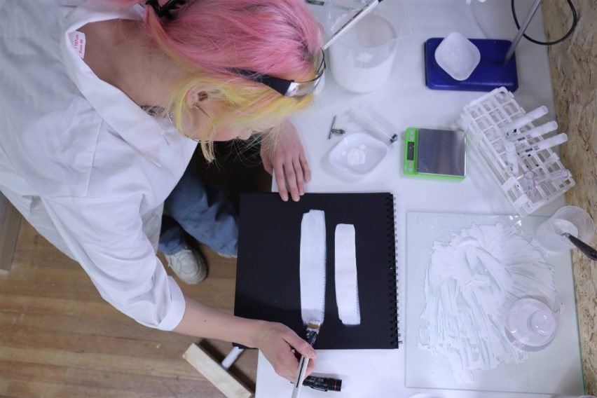 A woman painting with White 2.0 on black paper