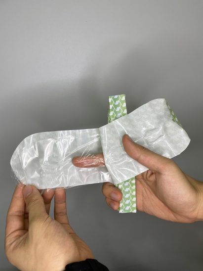 A hand showing how to wear a unisex condom