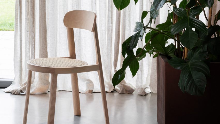 A photograph of the Brulla chair in natural ash in front of draped curtains