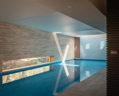 Swimming pool with brick walls, blue tiles and a low window