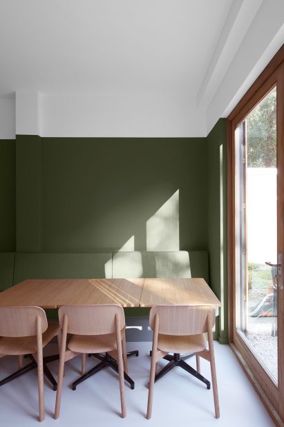 Staff breakout area of Dentista clinic with freen walls and wooden tables and chairs