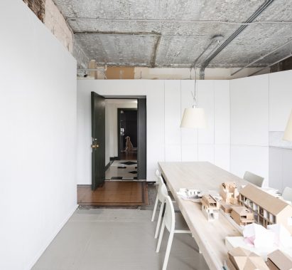 Meeting room with long wooden table, exposed concrete ceiling and tiled entrance in D'Arcy Jones Architects' self-designed studio in Vancouver