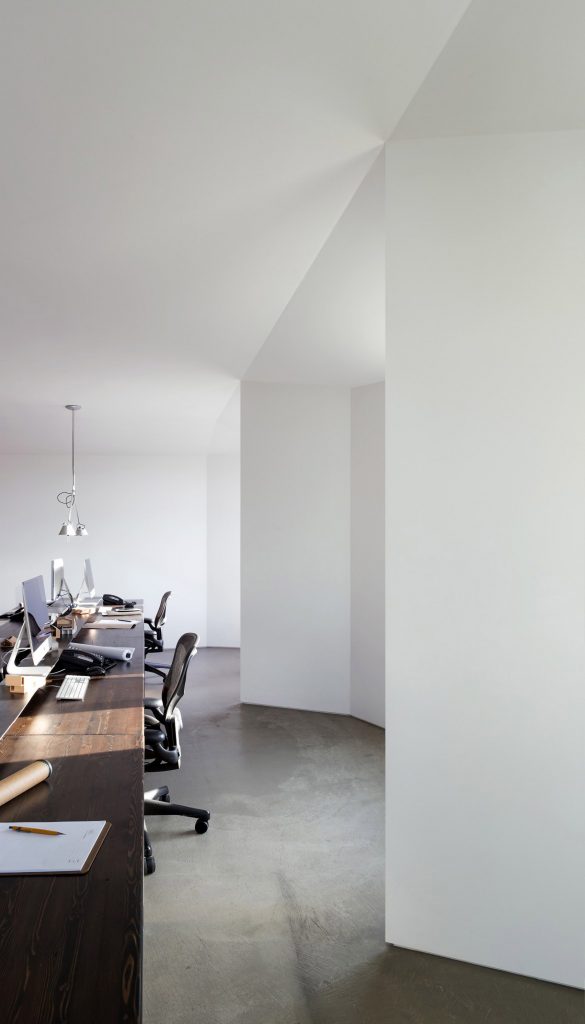 Long wooden work desk in white-painted workroom of Vancouver architecture practice